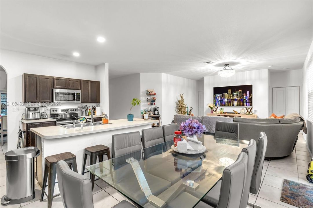 Kitchen featuring dark wood cabinetry, an integrated breakfast bar, and stainless-steel appliances, complemented by tile flooring and recessed lighting