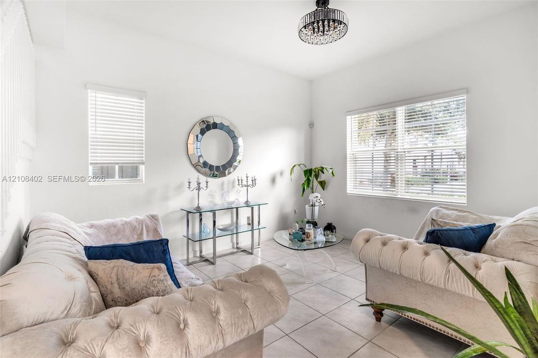 Neutral-toned tile flooring, multi-pane windows with integrated blinds, and a crystal-accented flush-mount chandelier