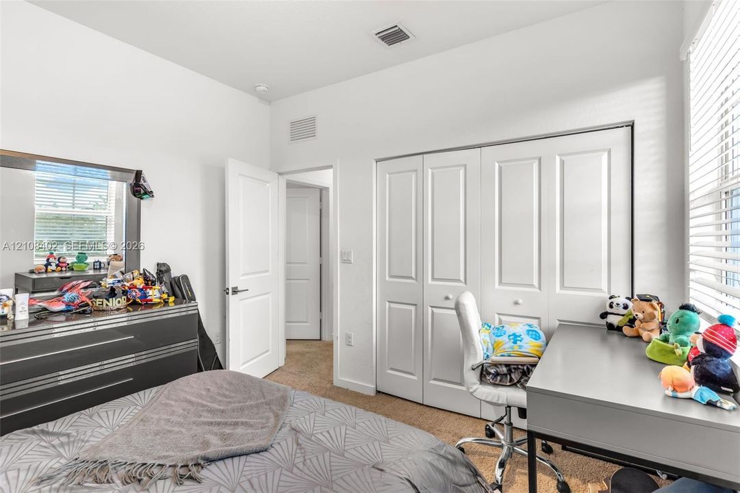 Room featuring neutral wall tones, carpeted flooring, white multi-panel interior doors, and a spacious closet with white bi-fold doors