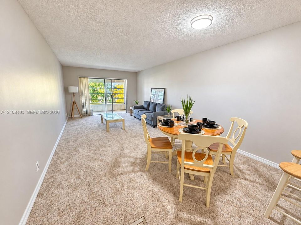Neutral-toned carpeted flooring, flush-mount ceiling lighting, and cious living and dining area featuring sliding glass doors that fill the space with natural light and provide convenient access to the outdoors, creating a bright and welcoming atmosphere.