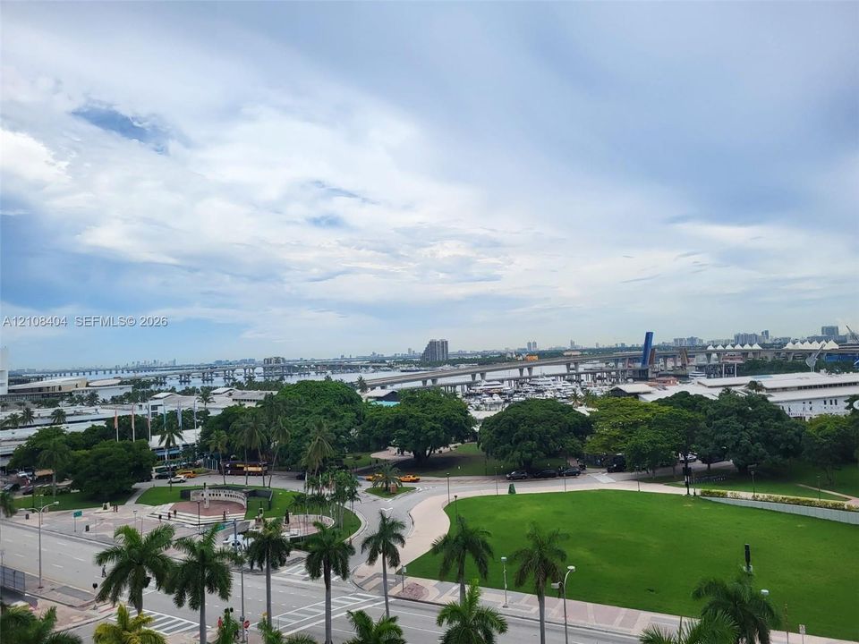 Panoramic cityscape featuring mature tropical landscaping, expansive manicured lawn, paved pathways, and harbor-front proximity