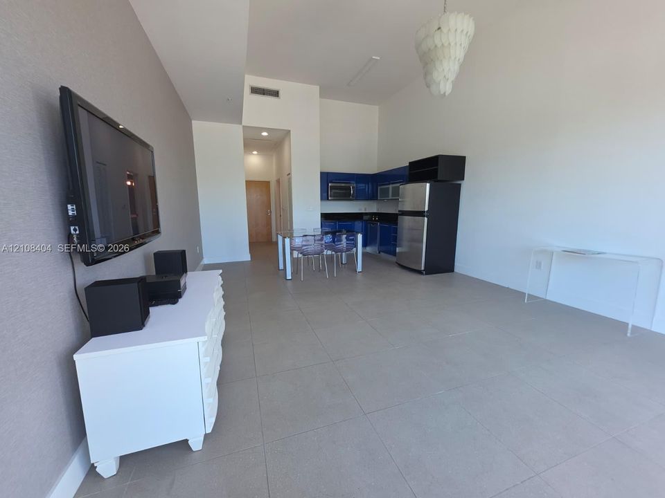 Open-concept floor plan featuring high ceilings, large-format tile flooring, textured wall accents, and custom blue cabinetry