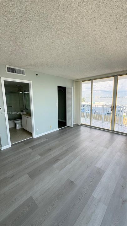 Wood-finish flooring, full-height sliding glass doors with balcony access, and dual interior doorways