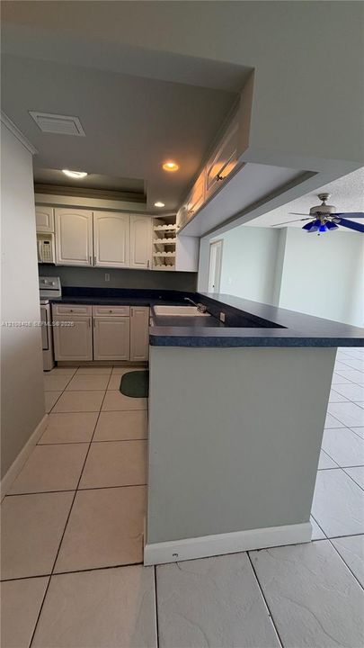 Kitchen featuring white cabinetry, solid-surface countertops, a breakfast bar, built-in wine rack, and tile flooring