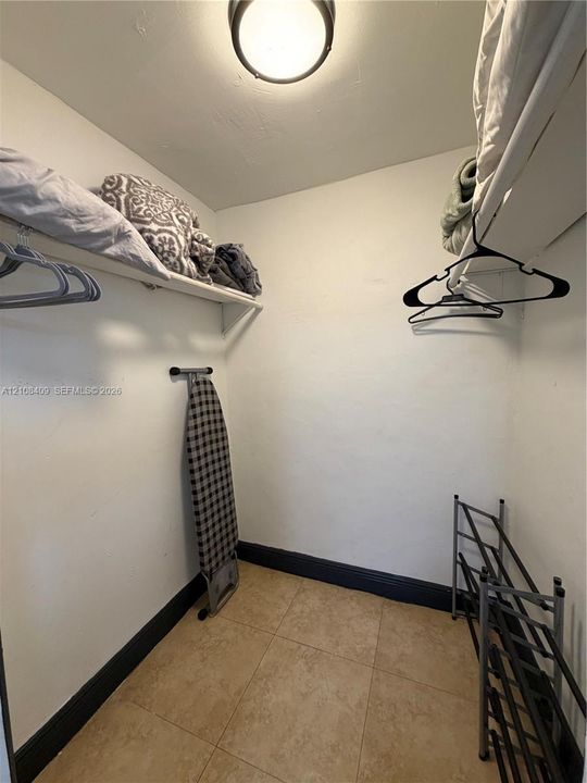 Storage area featuring tile flooring, ceiling-mounted lighting, and built-in shelving