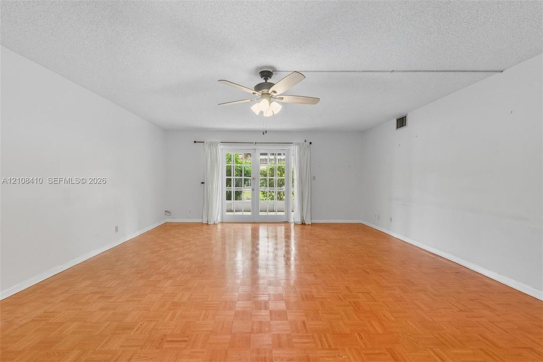 Parquet wood-finish flooring, ceiling fan with integrated lighting, and glass-paned French doors