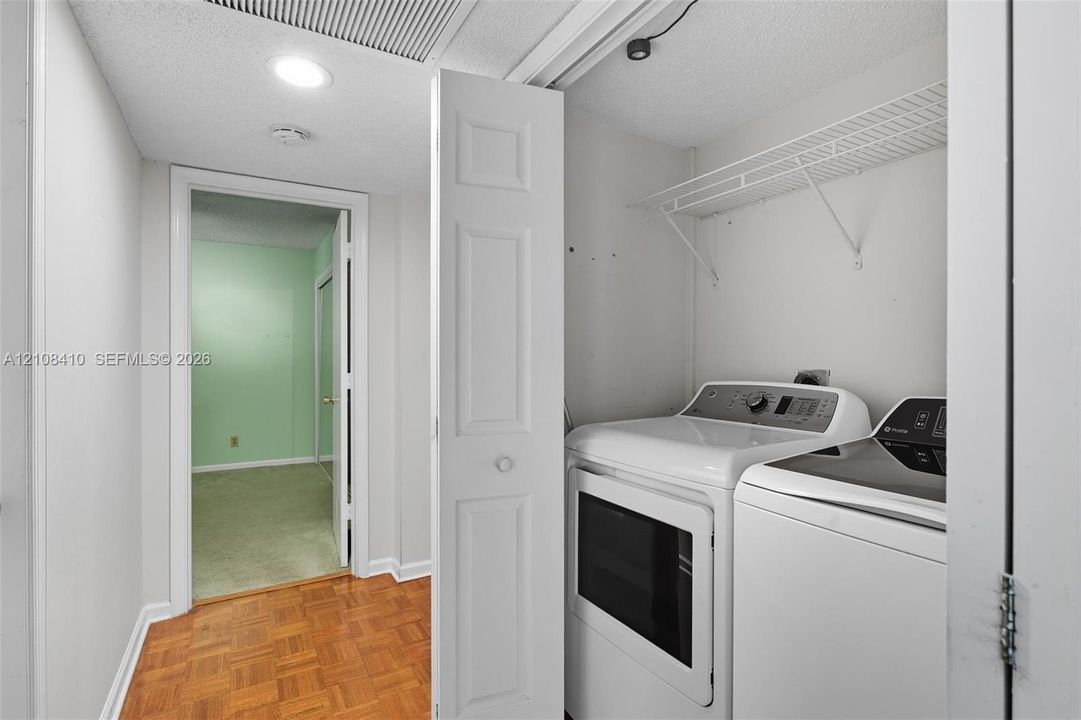 Laundry closet featuring white bifold doors, wire shelving, and wood-finish parquet flooring