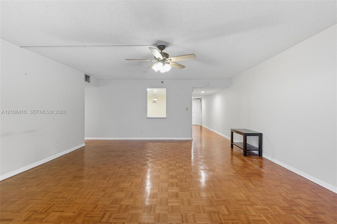 Parquet wood-finish flooring, ceiling fan with integrated light fixture, and interior pass-through opening