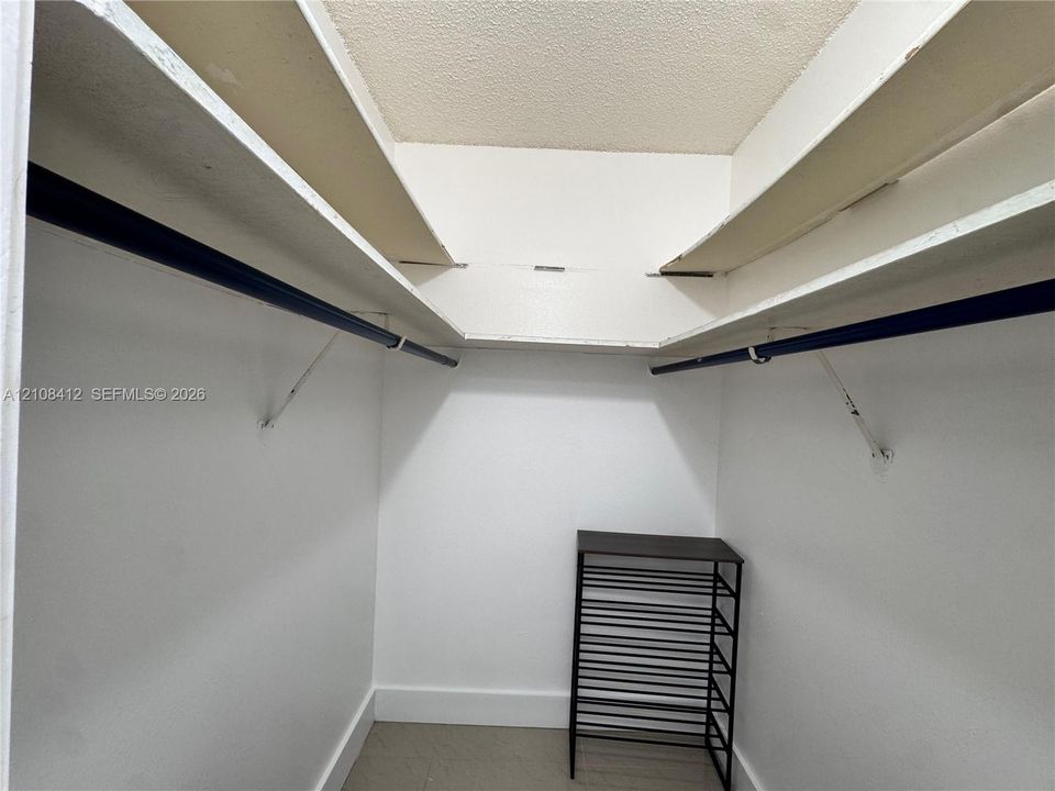 Storage space featuring white built-in shelving and dual hanging rods