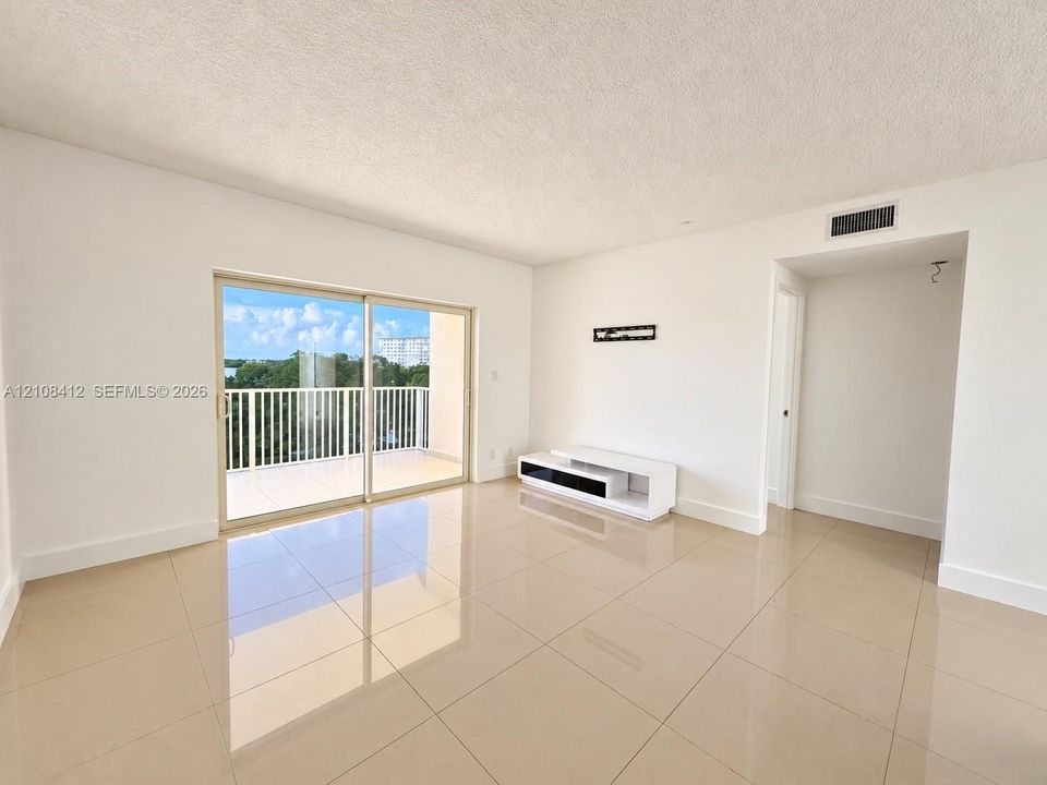 Interior space featuring large-format tile flooring, sliding glass doors providing outdoor access, and a balcony with white metal railings