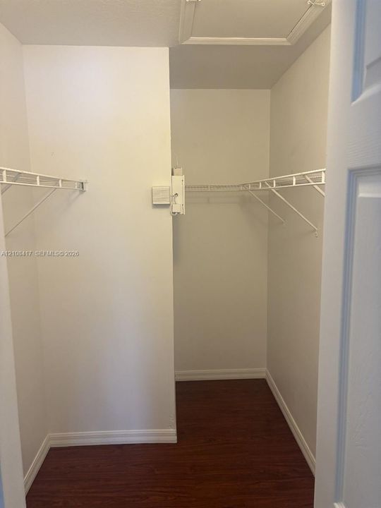 Walk-in closet featuring wood-finish flooring and dual-level coated wire shelving