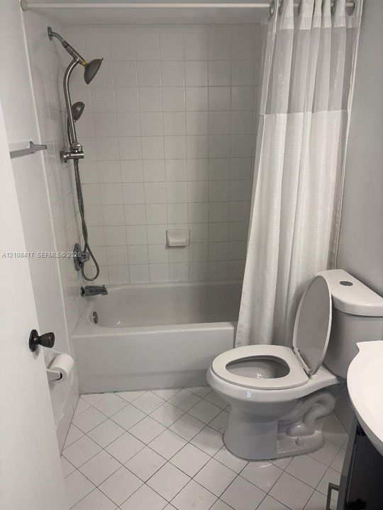 Bathroom featuring a soaking tub, ceramic tile surround, adjustable handheld shower fixture, and diamond-patterned floor tiling