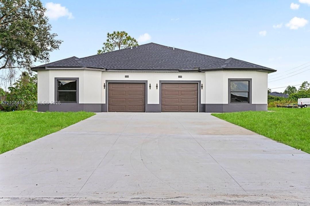 Stucco exterior with contrasting trim, dual garages, asphalt shingle roof, and a paved concrete driveway
