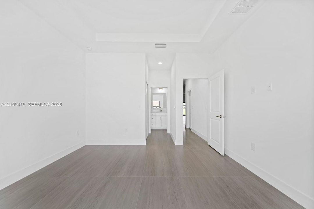 Tray ceiling, wood-finish flooring, recessed lighting, and white multi-panel interior door