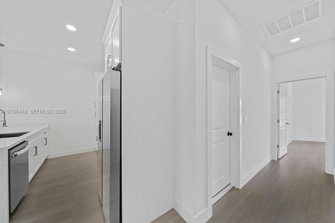 Kitchen area featuring white cabinetry, stone-finish countertops, stainless steel appliances, and wood-finish flooring