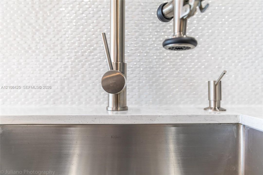 Brushed nickel commercial-style pull-down faucet, stainless steel undermount sink, solid surface countertop, and textured white tile backsplash