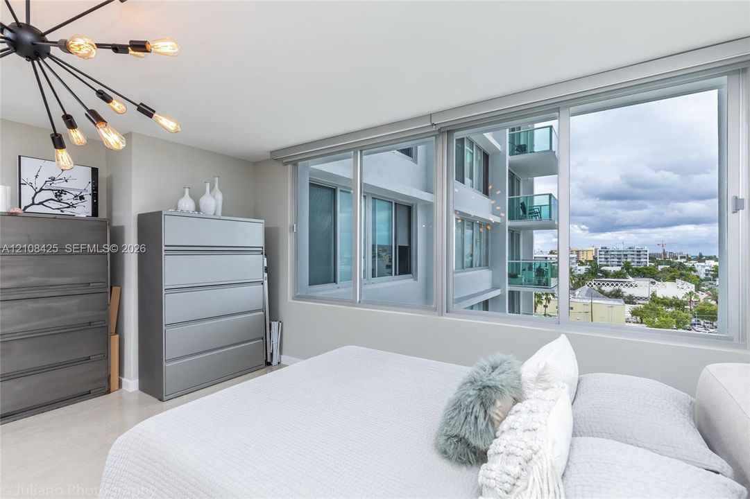 Expansive sliding glass windows, contemporary multi-arm sputnik-style ceiling light fixture, neutral wall color, and smooth-finish flooring