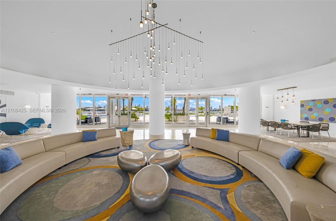 Open-concept interior featuring high ceilings, multi-pendant lighting fixture, circular support columns, and expansive floor-to-ceiling glass doors