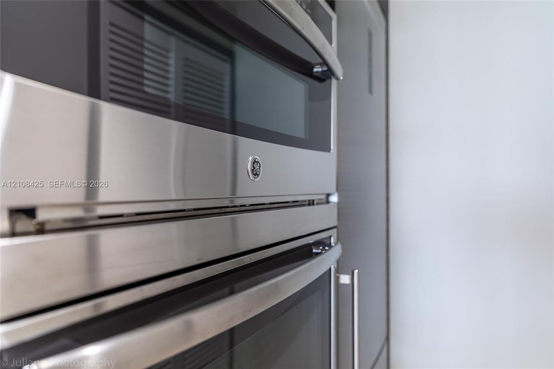 Stainless steel wall-mounted double oven featuring a built-in microwave, integrated touch controls, and sleek handles