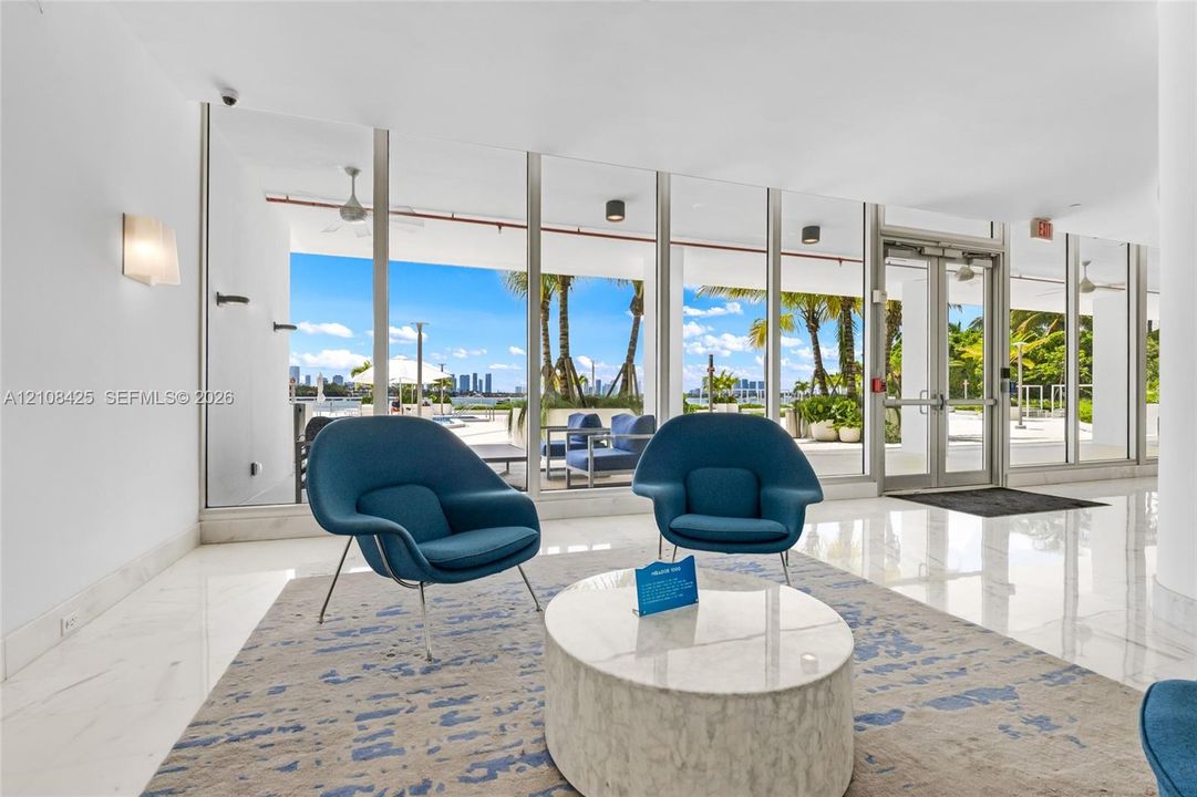 Floor-to-ceiling glass windows, polished tile flooring, wall-mounted lighting fixtures, and double glass-pane entry doors