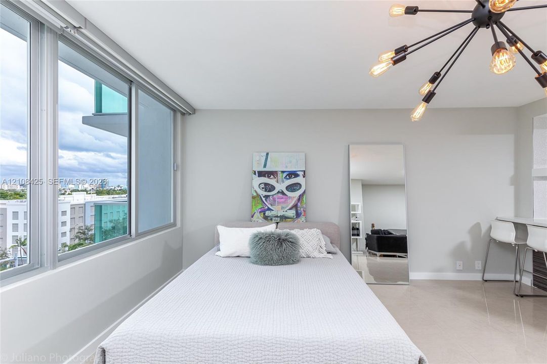 Floor-to-ceiling windows, polished tile flooring, industrial-style multi-arm chandelier, and built-in wall desk