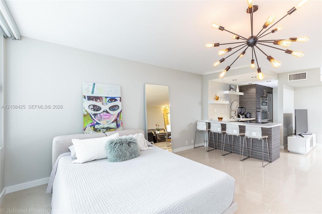 Sputnik-style chandelier, breakfast bar with horizontal wood-grain cabinetry, quartz countertops, and polished tile flooring