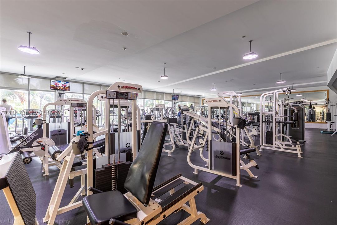 Fitness center featuring wall-to-wall mirrors, recessed lighting, rubberized flooring, and expansive windows