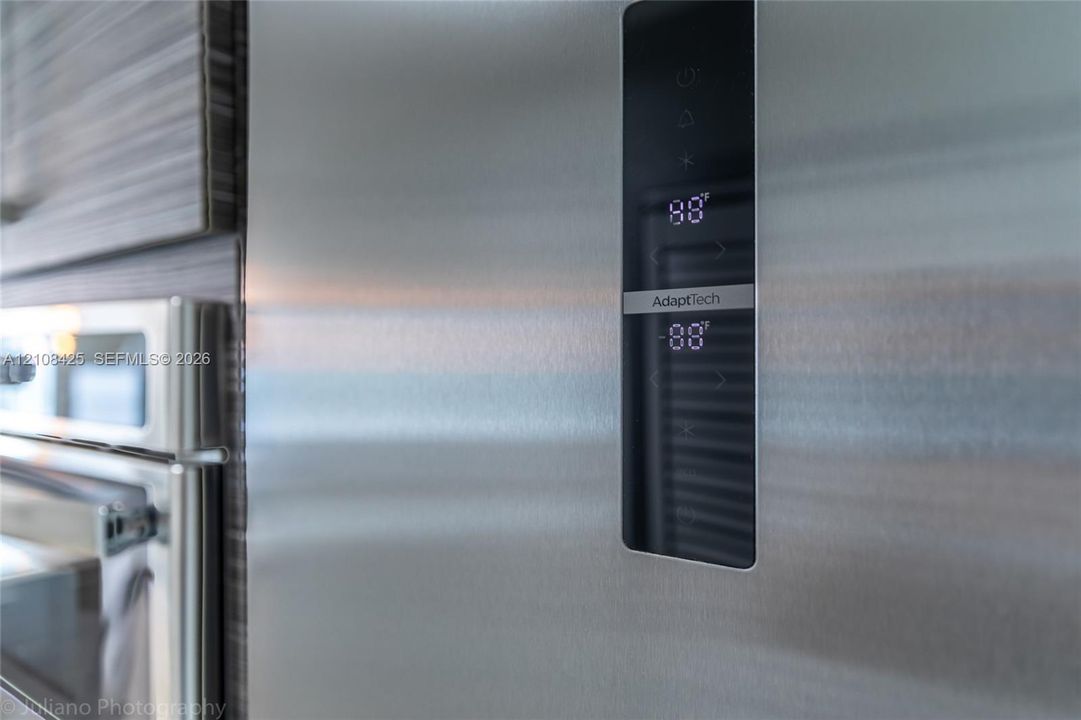 Stainless steel refrigerator featuring a digital touch-control interface and wood-grain textured cabinetry