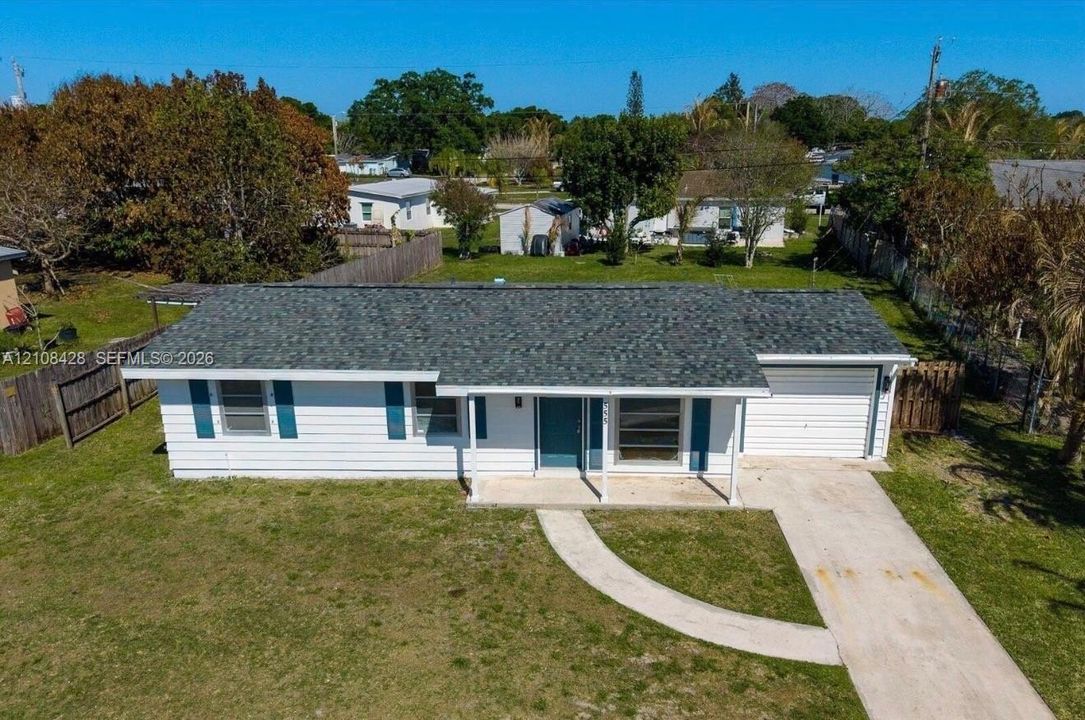 Single-story residence featuring white horizontal siding, a pitched asphalt shingle roof, blue window shutters, a concrete driveway, and an attached one-car garage