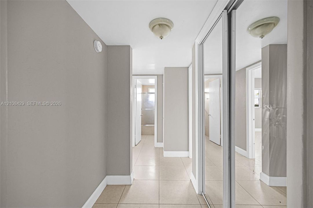 Hallway featuring tile flooring, sliding mirror-panel closet doors, and flush-mount ceiling light fixtures