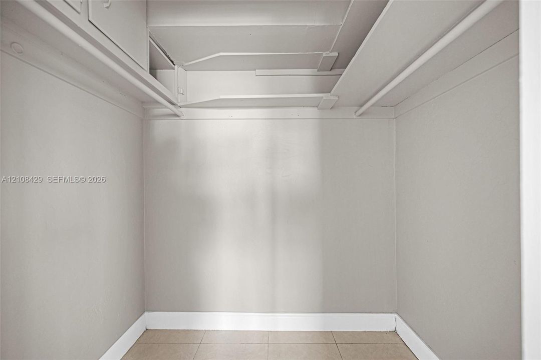 Storage space featuring tiled flooring, built-in shelving, and dual hanging rods