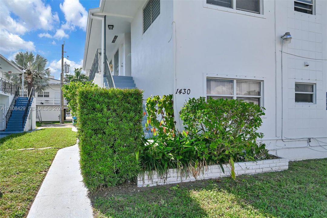 Stucco exterior featuring multi-level metal railings, integrated landscaping, white brick planter boxes, and concrete walkways