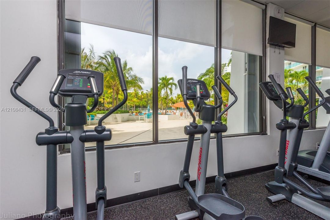 Fitness center featuring floor-to-ceiling windows, retractable solar shades, and industrial rubber flooring
