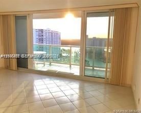 Floor-to-ceiling sliding glass doors, private glass-railed balcony, and large-format tile flooring