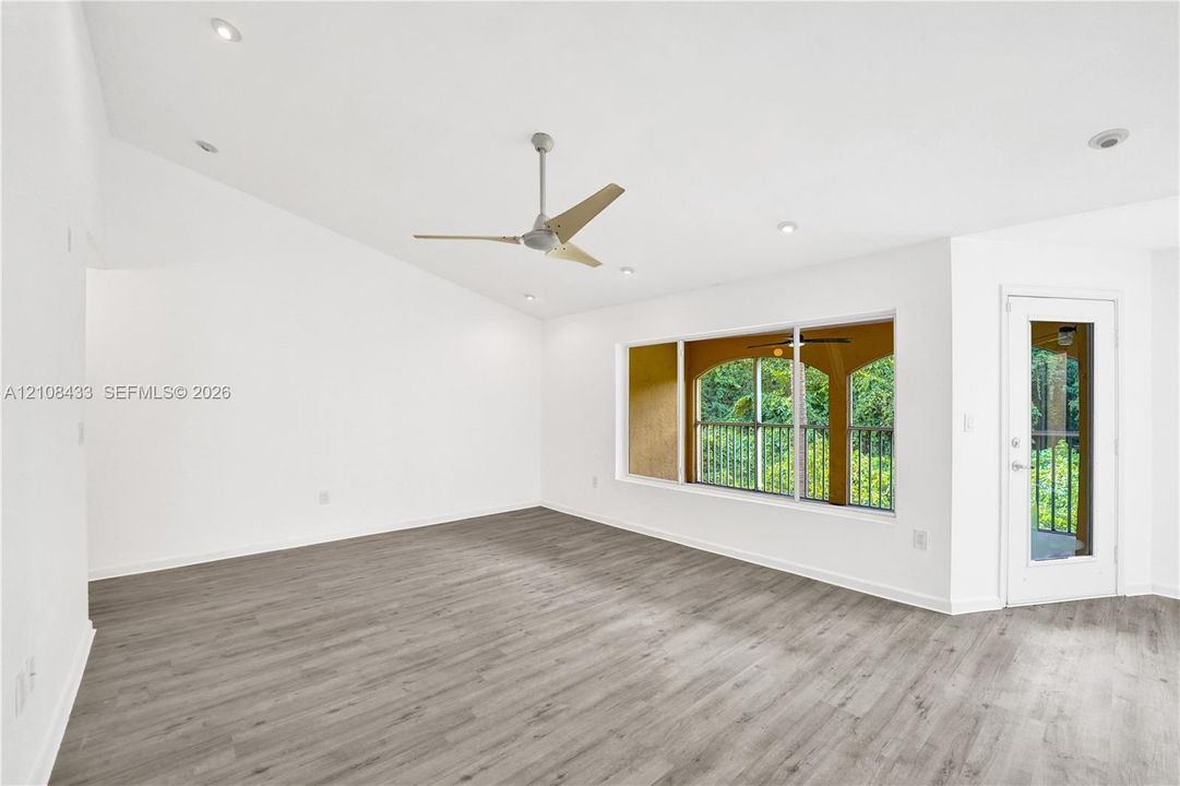Vaulted ceilings featuring recessed lighting, wood-finish flooring, a contemporary ceiling fan, and a glass-paneled exterior door