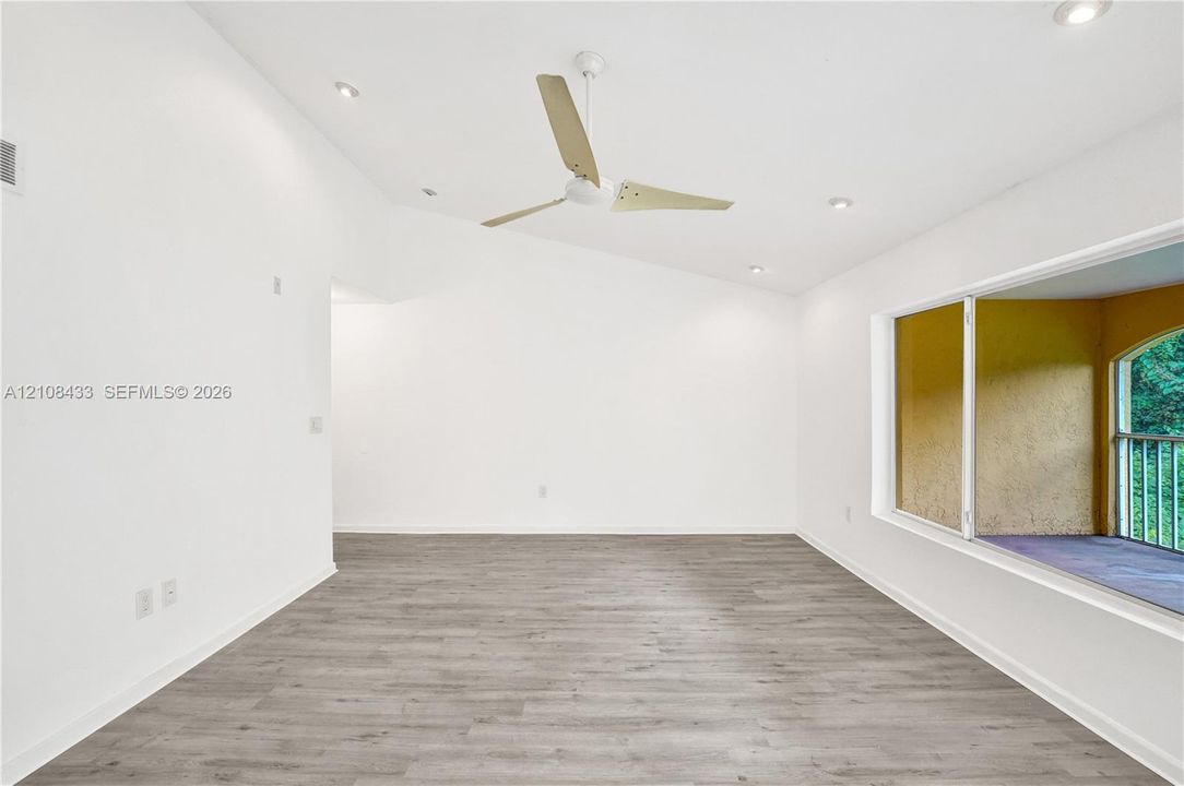 Vaulted ceiling with recessed lighting, wood-finish flooring, and a modern three-blade ceiling fan