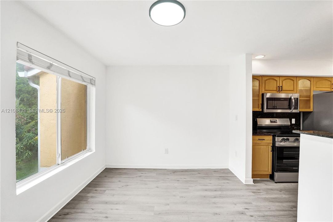 Wood-finish flooring, large sliding window, recessed lighting, and built-in cabinetry featuring stone countertops and stainless steel appliances