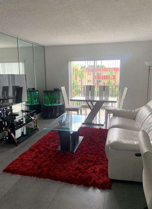 Large format tile flooring, floor-to-ceiling mirrored wall paneling, and sliding glass doors with access to an exterior balcony