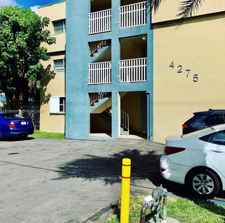 Multi-story exterior featuring a stucco facade, white metal balcony railings, and exterior staircases