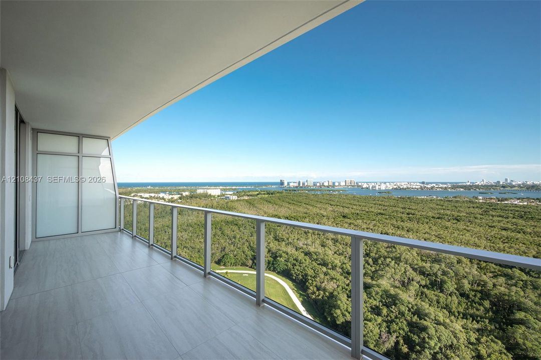 Covered balcony featuring wood-finish tile flooring, glass panel railing, and metal framing