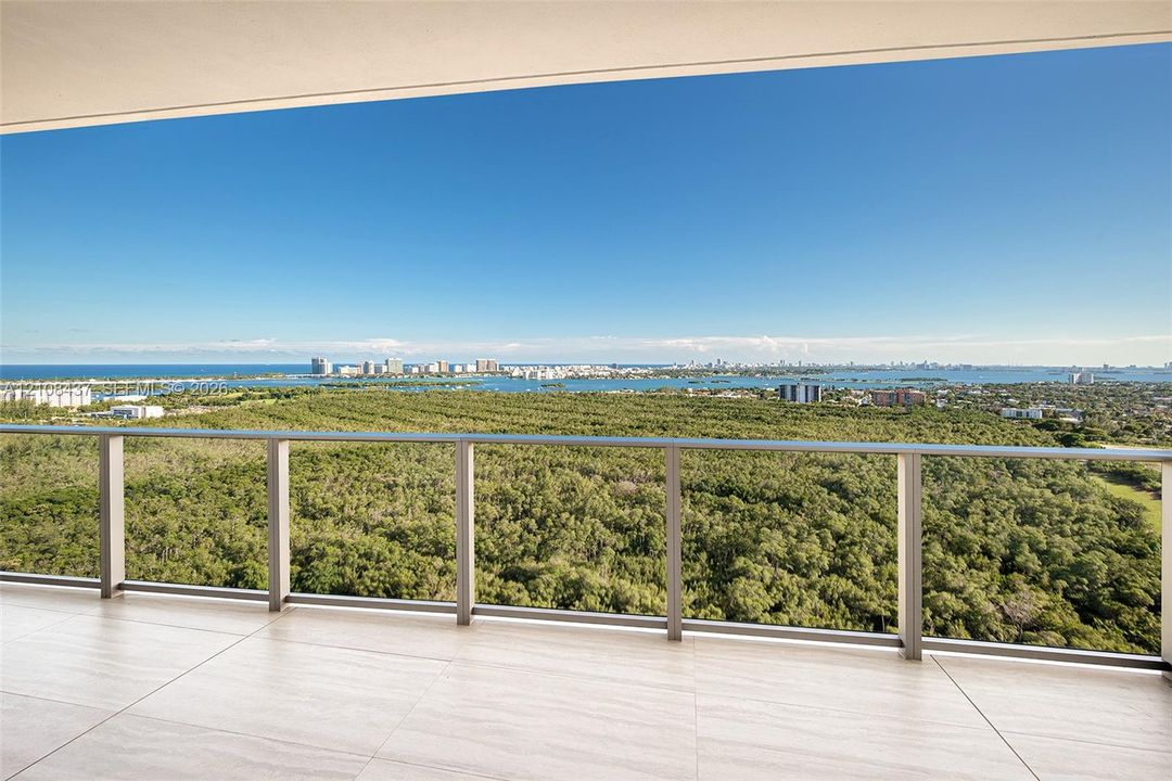 Covered balcony featuring large-format stone-finish tile flooring and a minimalist metal railing