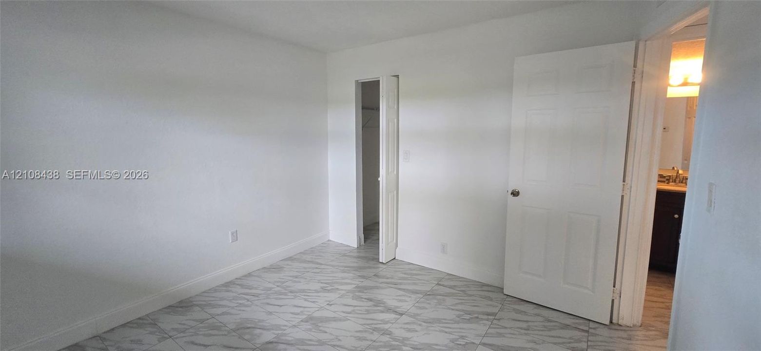 Neutral-toned interior space featuring stone-finish flooring and a walk-in closet with bifold door