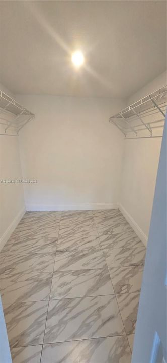 Walk-in closet featuring large-format tile flooring and dual-level wire shelving