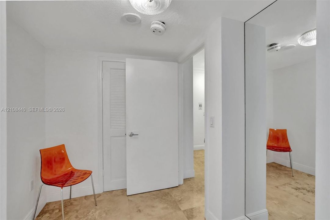 Interior space featuring stone tile flooring, full-height wall mirror, and a louvered closet door