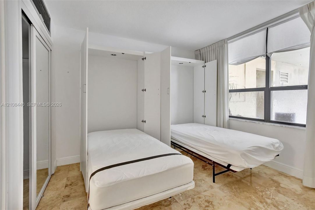 Built-in dual wall-mounted beds, stone-finish flooring, and sliding-door closets with mirrored panels