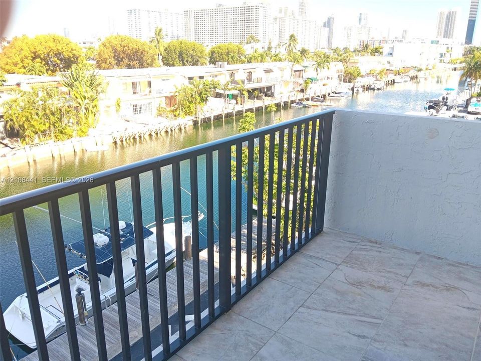 Private balcony featuring tile flooring and metal railing, overlooking the canal and waterfront area