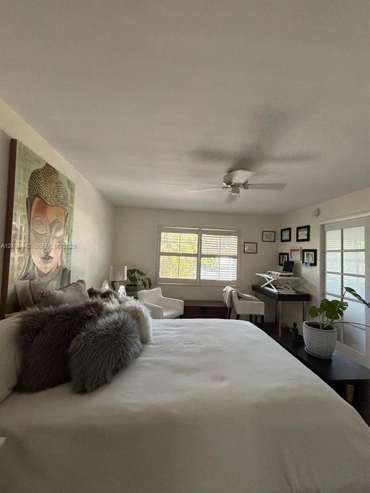 Room featuring white interior walls, plantation shutters, a ceiling fan, and multi-lite French doors