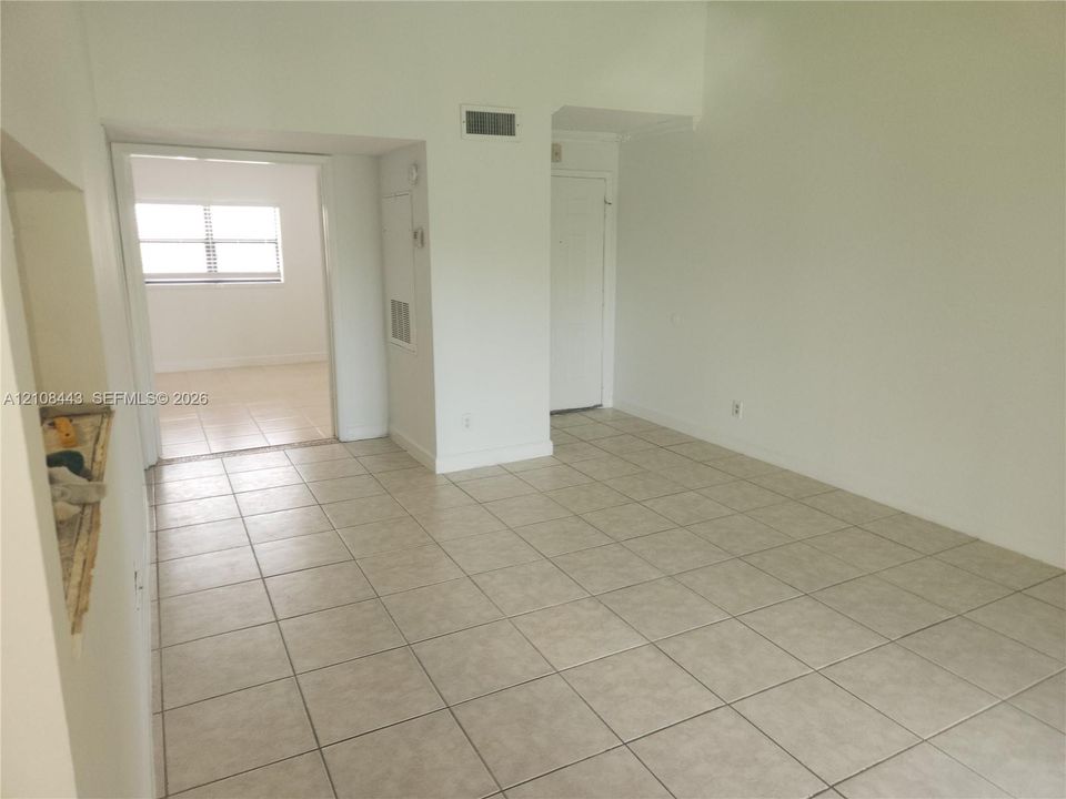 Neutral tile flooring, expansive wall space, and multiple interior openings with white-finish trim