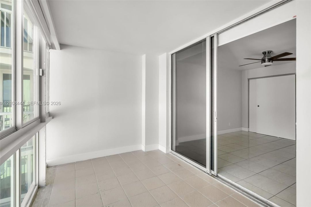 Enclosed sunroom featuring expansive multi-pane windows, large-format tile flooring, and a sliding glass door system