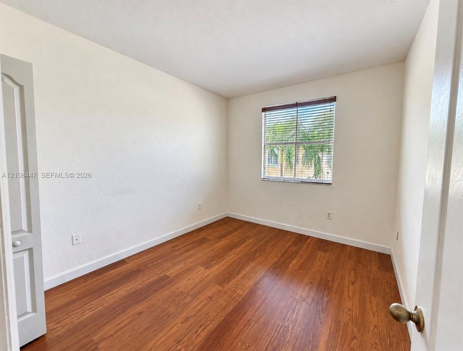 Room featuring wood-finish flooring, neutral wall paint, and a single-panel window with integrated blinds